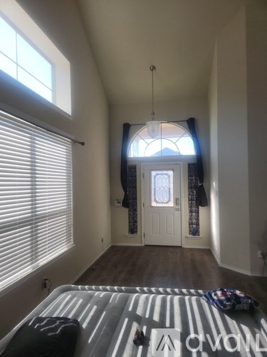 A bedroom with a bed and a window with blinds.
