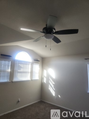 A room with a ceiling fan and a window with blinds.