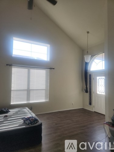 A bedroom with a bed, a window with blinds, a ceiling fan, and a lamp.