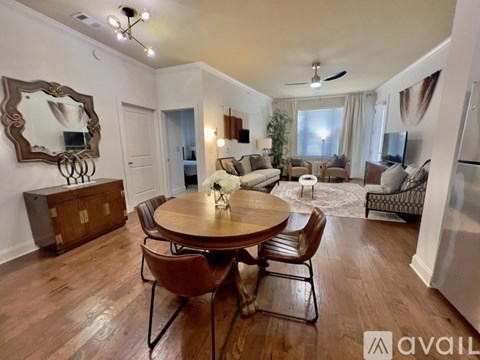 A well-lit living room with a wooden dining table and chairs.