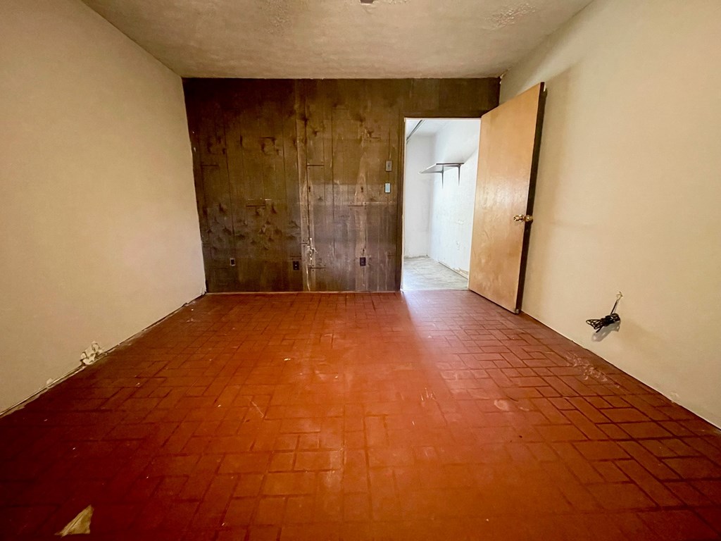 A room with a red tiled floor and a door on the right.