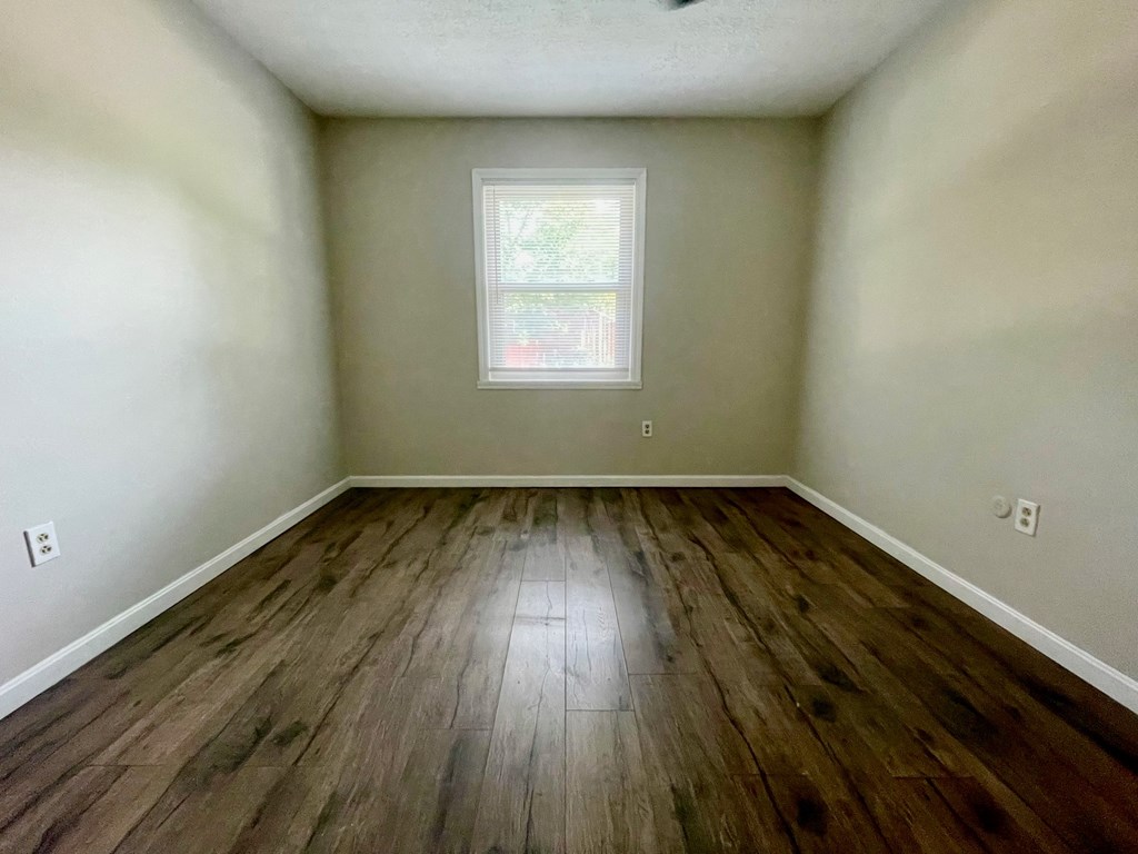 A room with wooden flooring and a window.
