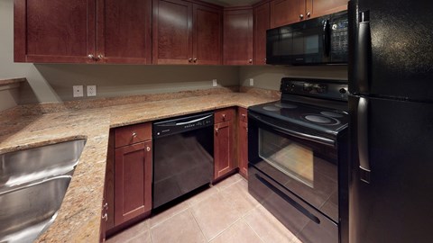 A kitchen with black appliances and wooden cabinets.