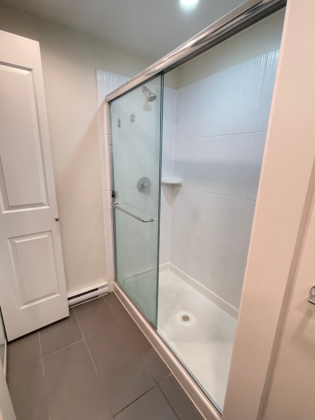 A white door is open to a bathroom with a glass shower stall.