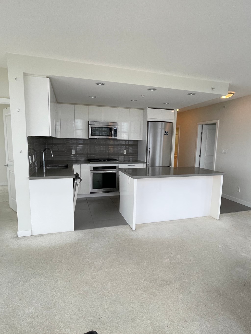 A kitchen with white cabinets and a black countertop.