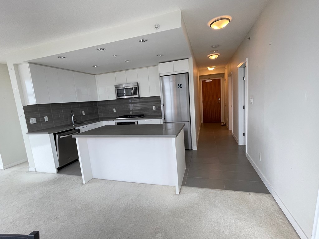 A modern kitchen with a large island and a microwave above it.