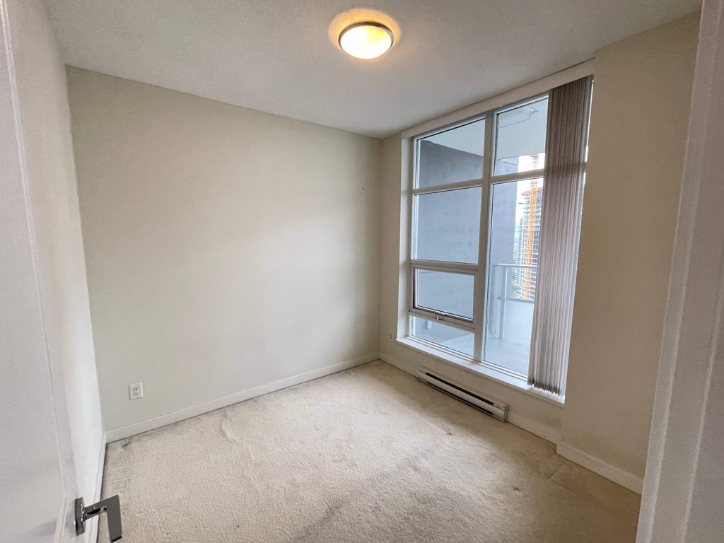 A room with a window and a carpeted floor.