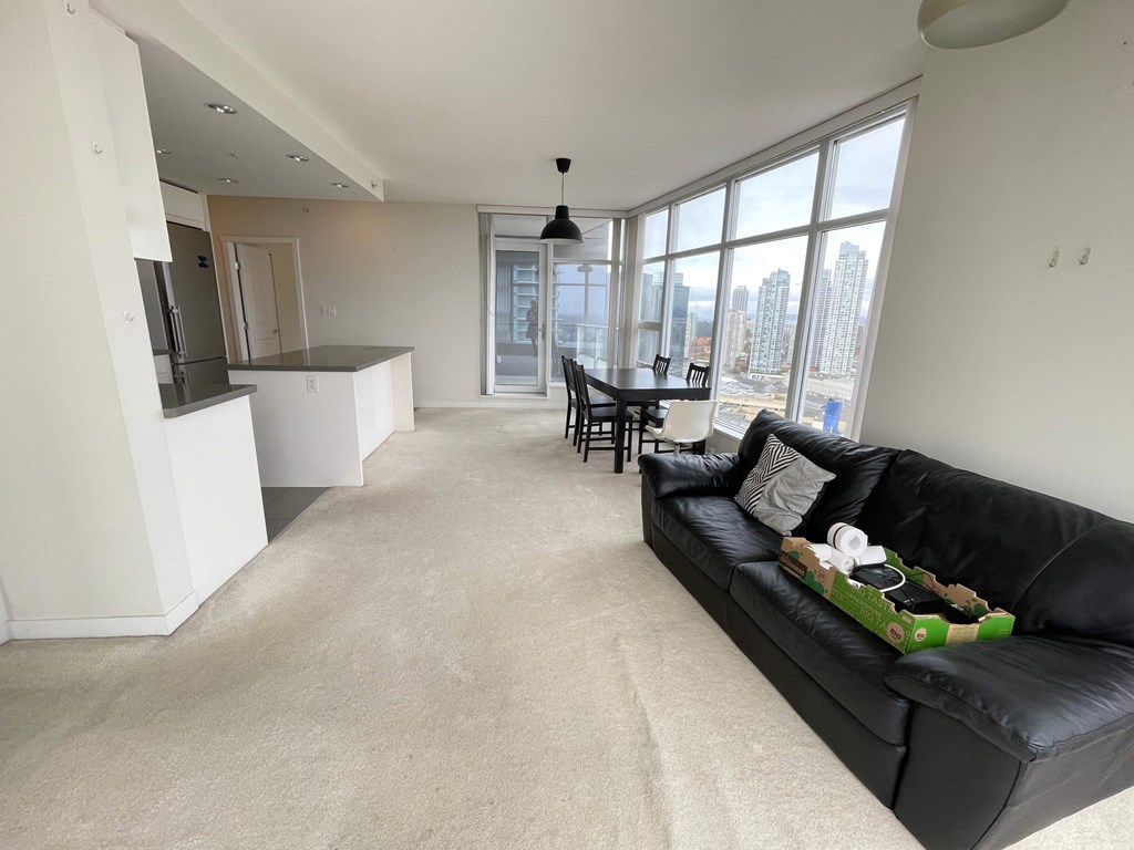 A black couch with a green pillow is in the middle of a living room.
