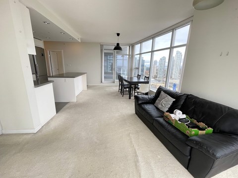A black couch with a green pillow is in the middle of a living room.