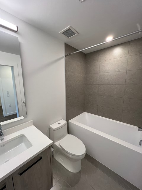 A white toilet sits next to a white bathtub in a bathroom.