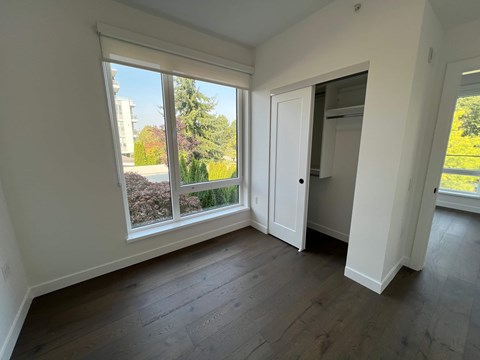A room with a large window and a view of a garden and a building outside.