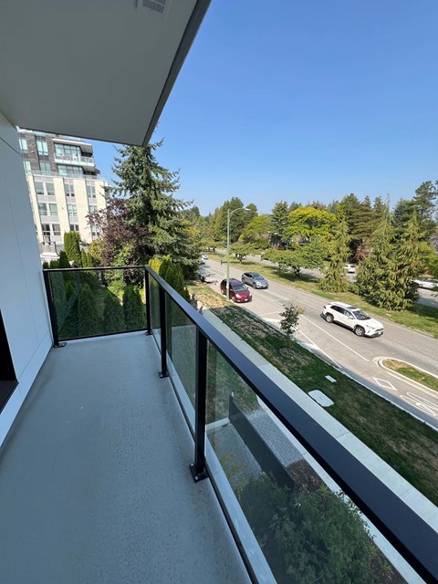 A balcony overlooks a street with cars and trees.