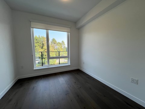 A room with a large window and wooden flooring.