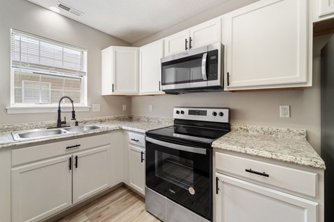 A kitchen with white cabinets and a granite countertop.
