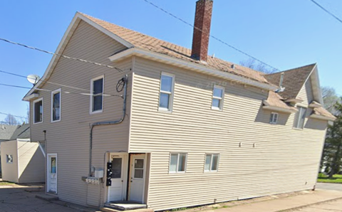 A two-story house with a white siding exterior and a brown roof.