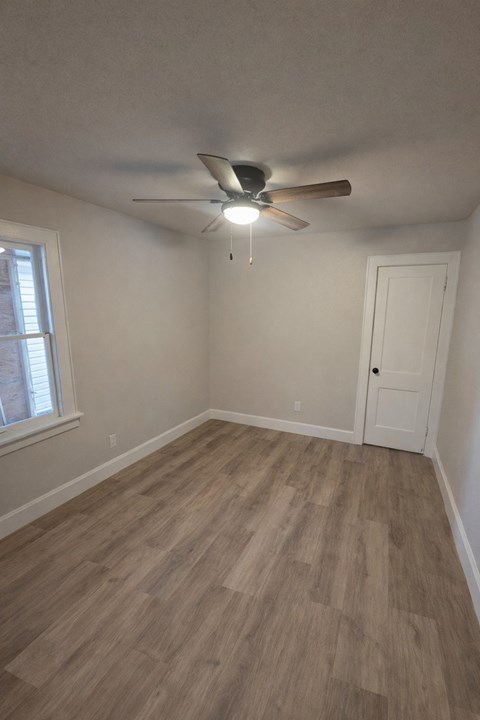 A room with a ceiling fan and wooden flooring.