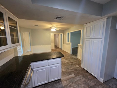 A kitchen with a black counter top and white cabinets.