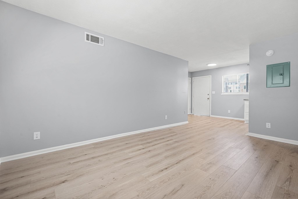 A room with wooden flooring and a grey wall.