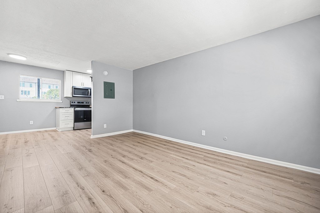 A spacious room with wooden flooring and a kitchenette in the corner.