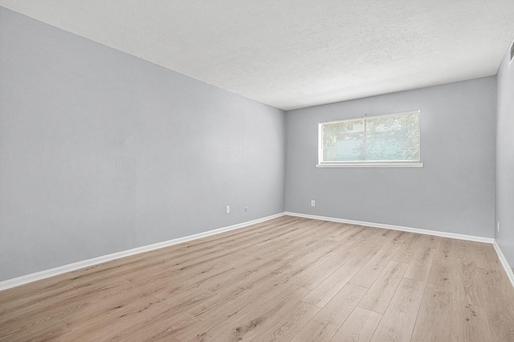 A room with wooden flooring and a window with blinds.