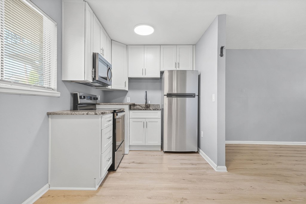 A kitchen with white cabinets and a granite countertop.