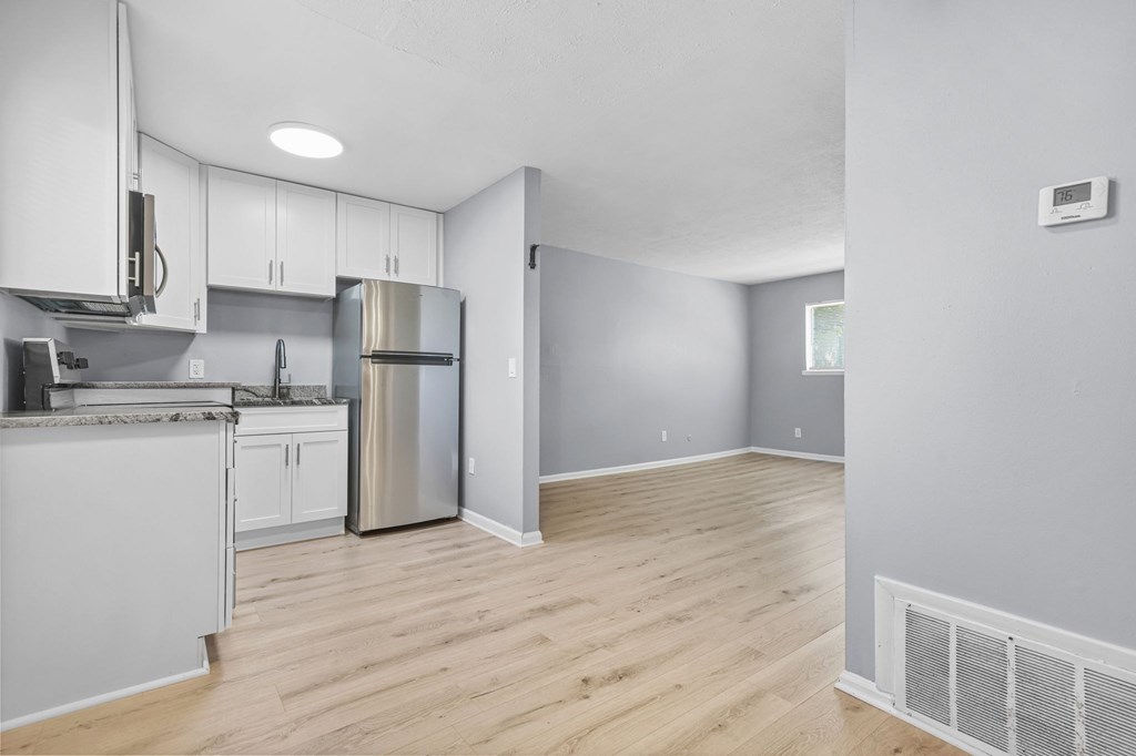 A kitchen with white cabinets and a stainless steel refrigerator.