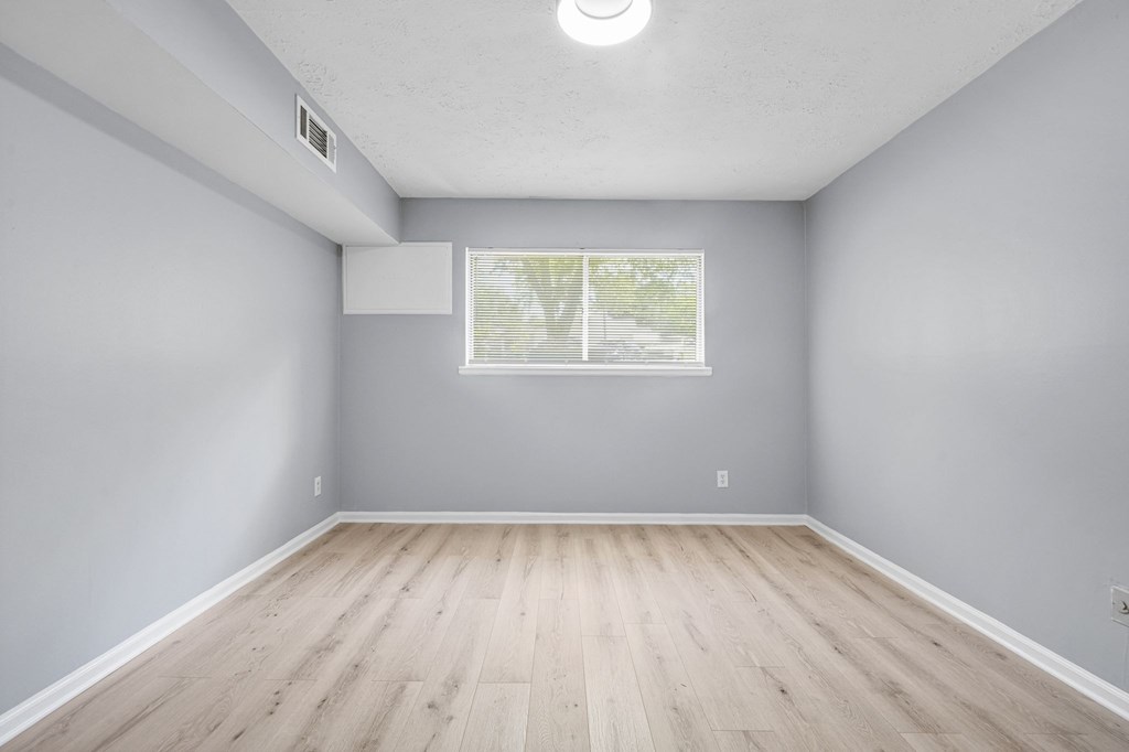 A room with a window and wooden flooring.