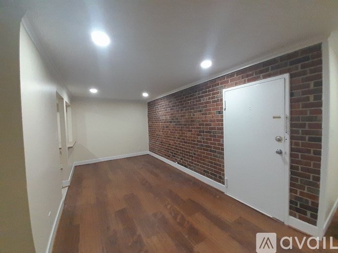 A room with a white door and a brick wall.