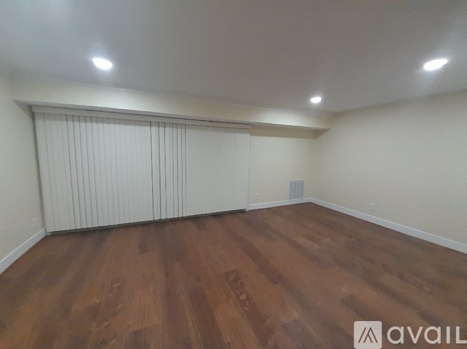 A room with wooden flooring and a window with blinds.