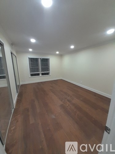 A room with wooden flooring and a window with blinds.