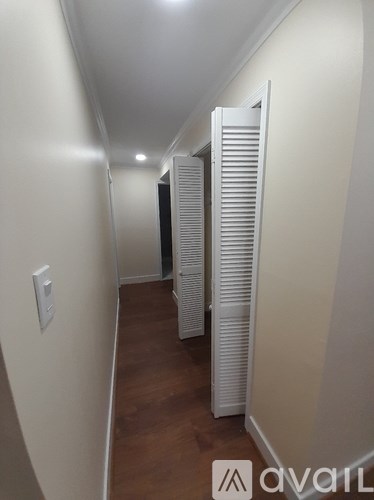 A long hallway with white walls and wood floors.