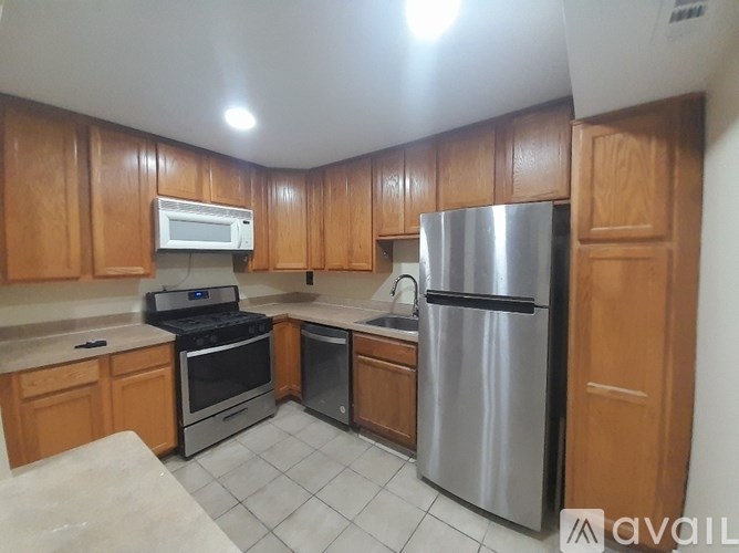 A kitchen with wooden cabinets and a stainless steel refrigerator.
