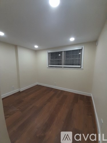 A room with wooden flooring and a window with blinds.