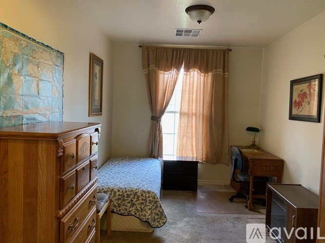 A room with a bed, desk, and chair.