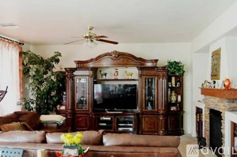 A living room with a brown leather couch and a wooden entertainment center.