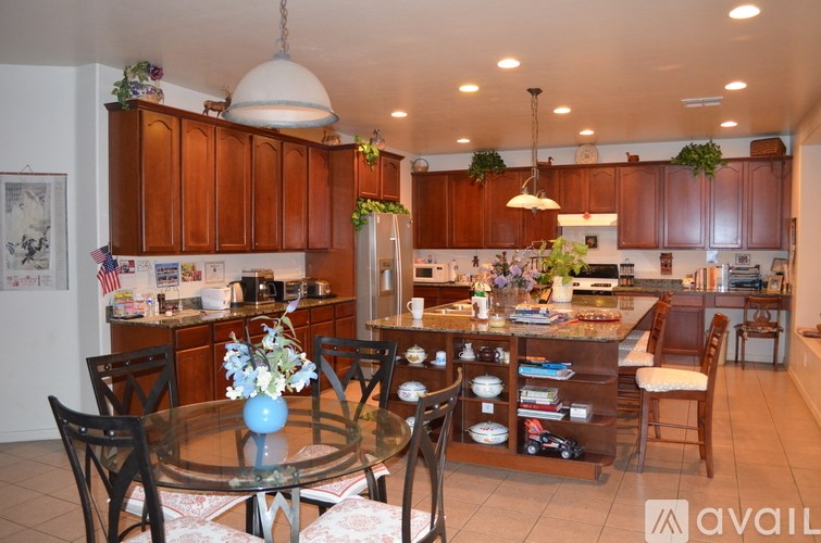 A kitchen with brown cabinets and a glass table with chairs around it.
