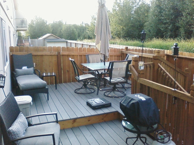 A patio with a table, chairs, and an umbrella.