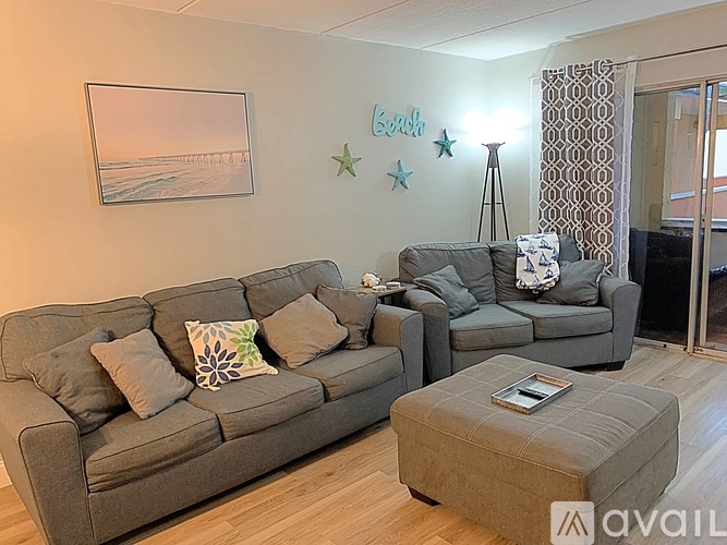 A living room with a grey couch and a grey ottoman.