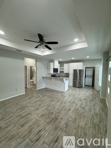 A spacious kitchen with a fan and wooden flooring.