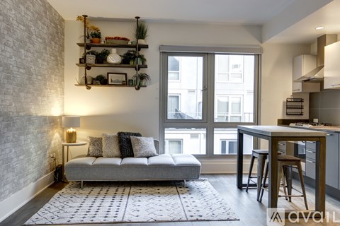 A living room with a grey sofa and a white brick wall.