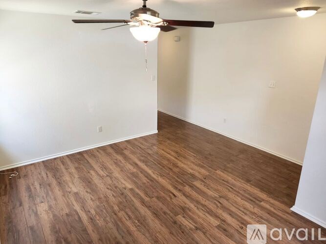 A room with a ceiling fan and wooden flooring.