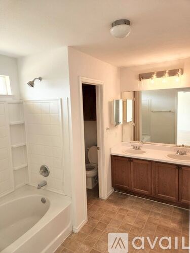 A bathroom with a tub, sink, mirror, and toilet.