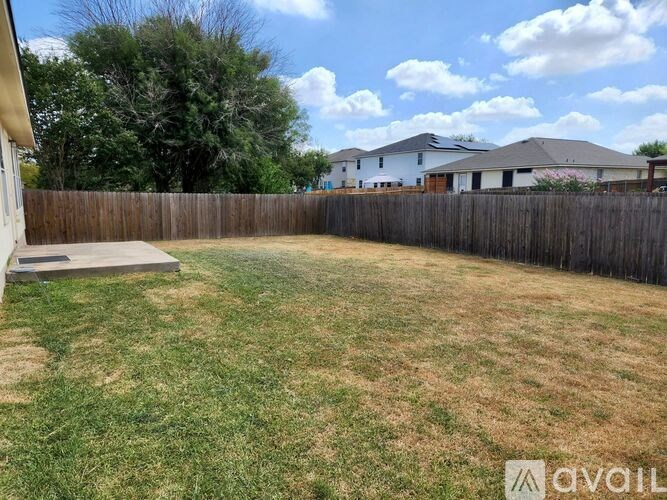 A backyard with a wooden fence and a small concrete slab.