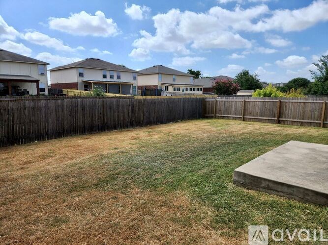 A backyard with a wooden fence and a concrete slab.