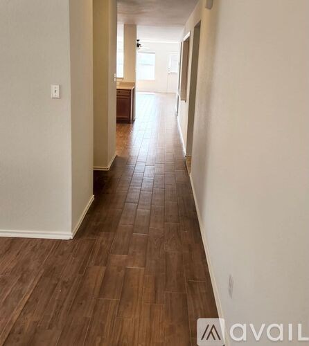 A long hallway with wood flooring and white walls.