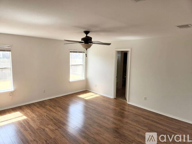 A room with a ceiling fan and wooden flooring.