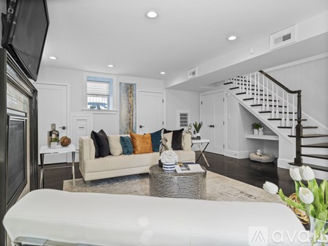 A living room with a white couch and a television on the wall.