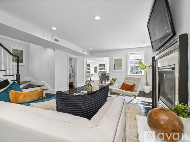 A living room with a white couch and a television on the wall.