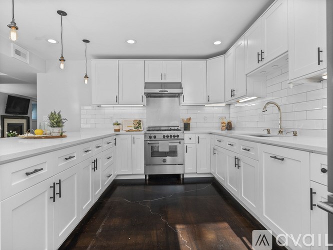 A modern kitchen with white cabinets and a dark wood floor.