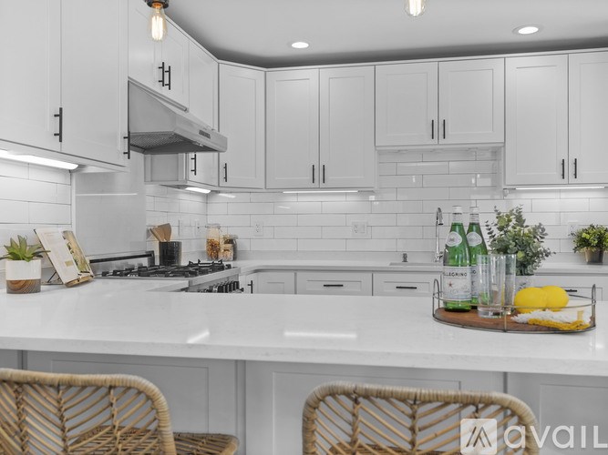 A kitchen with white cabinets and a marble countertop.